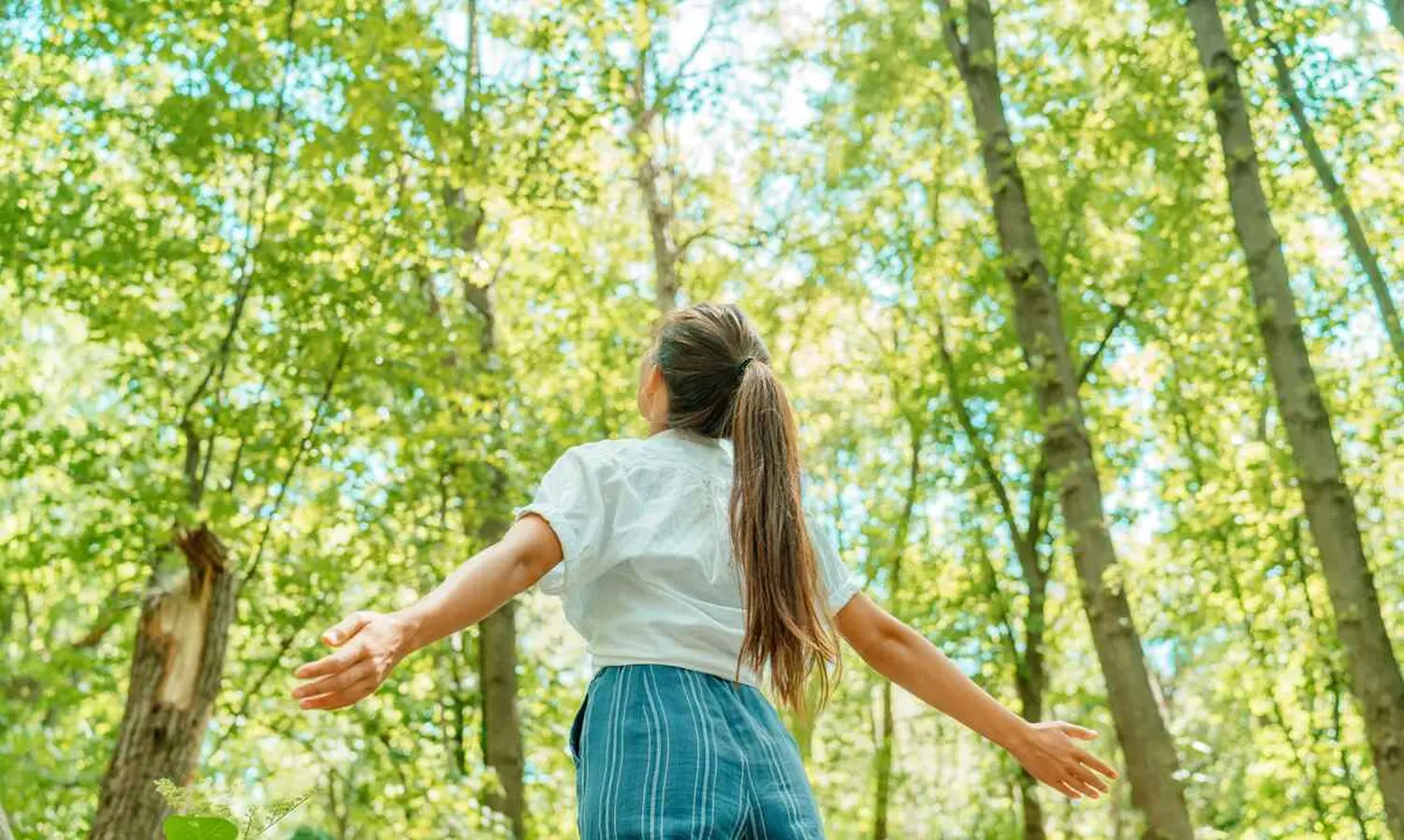 Freie Frau atmet saubere Luft im Naturwald