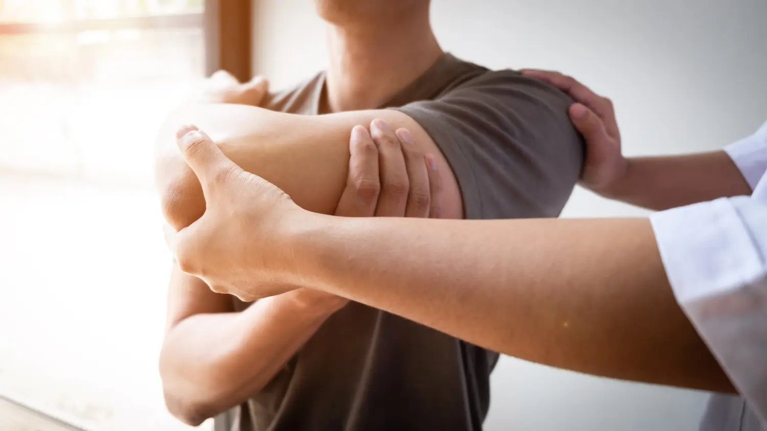 Therapist treating a male injured by rotator cuff stretching method.