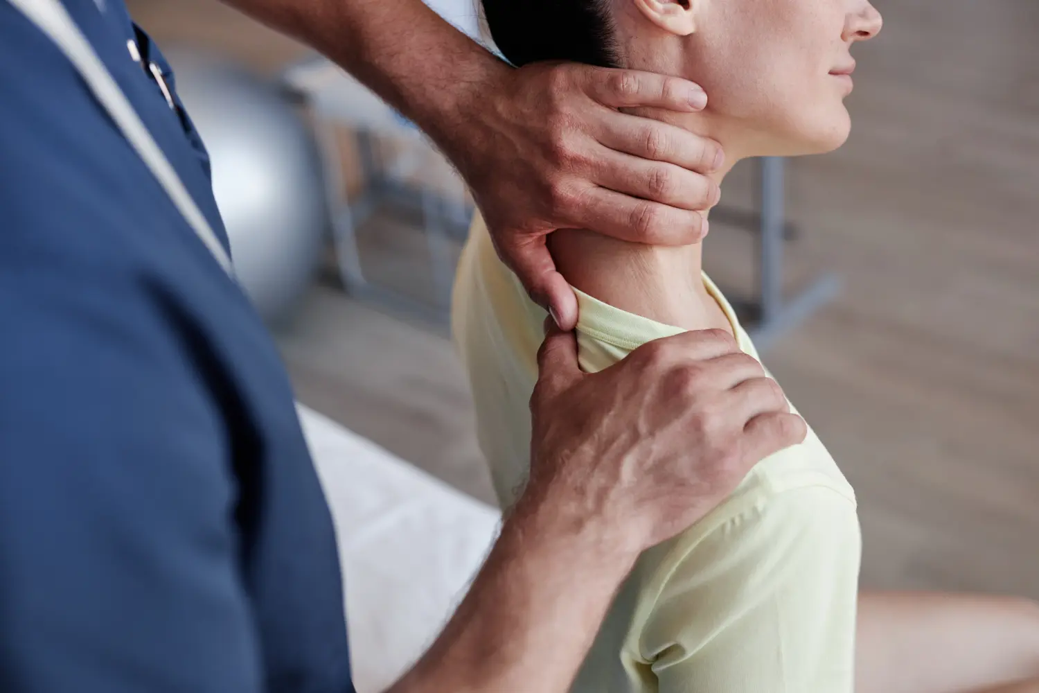 Nahaufnahme eines manuellen Therapeuten, der während der Therapie in der Klinik den schmerzenden Nacken einer jungen Frau massiert